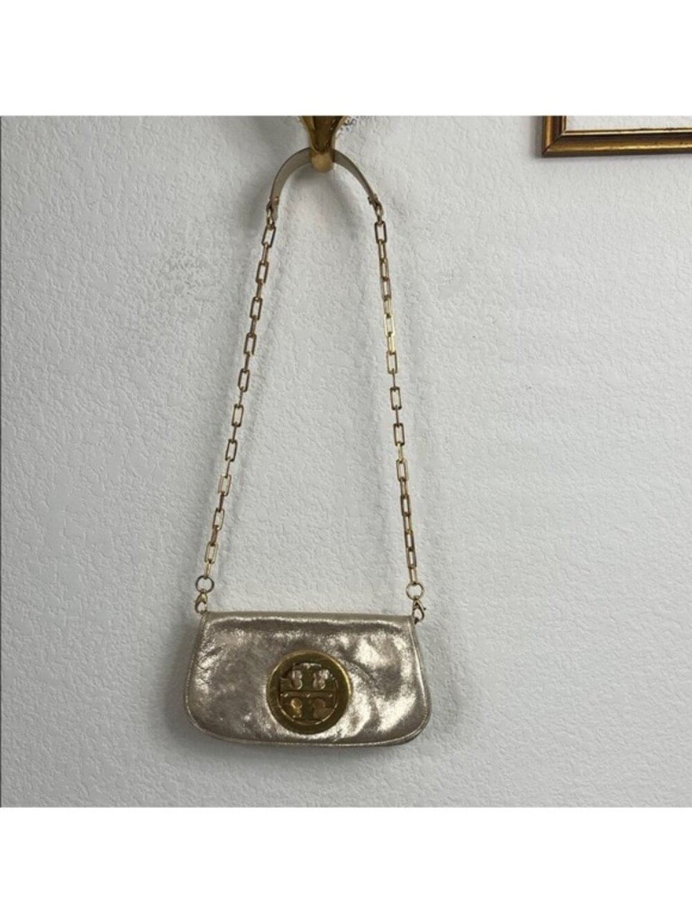 The Reva Metallic Clutch is defined by a curved shape and bold hardware. Wear it